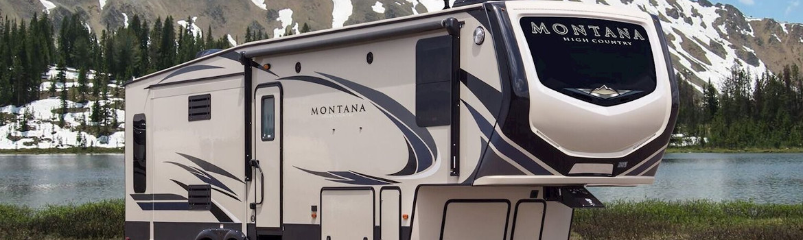A Keystone RV Montana High Country camped out next to a lake near mountains